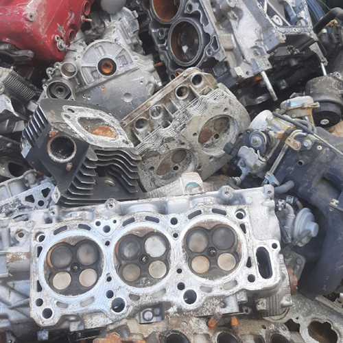 An alluminuim engine block with a pile of other car part scraps